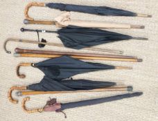 A collection of vintage umbrellas, parasols and walking canes including hallmarked silver mounted