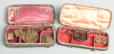 Two shagreen or similar cased travelling beam scales with weights. Width of larger case 11cm
