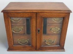 Oak desk top or similar cabinet the bevelled glazed doors opening to reveal six drawers, width 34cm
