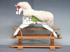 A wooden rocking horse painted in dapple grey with wool seat covering on rocker base with remnants