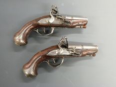 A pair of French flintlock hammer action pocket pistols, the ornately carved stocks decorated with