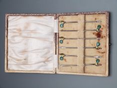 A boxed set of George V Art Deco hallmarked silver cocktail sticks with enamel finials depicting