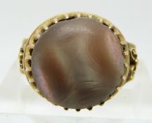 A yellow metal ring set with a shell cabochon with pierced shoulders (size J)