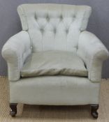 An upholstered button back tub chair raised on wooden legs and ceramic castors