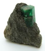 A hexagonal uncut emerald still attached to the matrix