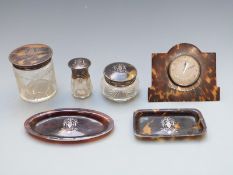 Six tortoiseshell pique work dressing table items comprising clock, three hallmarked silver lidded