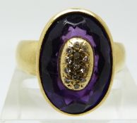 An 18ct gold ring set with a faceted purple stone and diamonds in an oval gold section to the