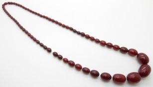 A graduated cherry amber necklace made up of 67 oval shaped beads, the largest bead 29x21mm, 69g
