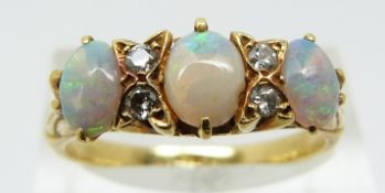 An 18ct gold ring set with three opal cabochons and four diamonds (size R)