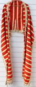 A striped cloak style garment with fringed braid and tassel trim