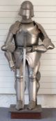 A replica suit of armour and sword on plinth including gorget, visor, breastplate, fan plate, grieve