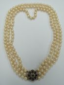 A three strand cultured pearl necklace with a 9ct white gold clasp set with nine round cut
