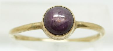 A gold ring set with a star ruby cabochon, size P