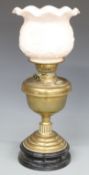 Brass oil lamp on black lacquered pottery base, the pale pink milk glass shade with embossed