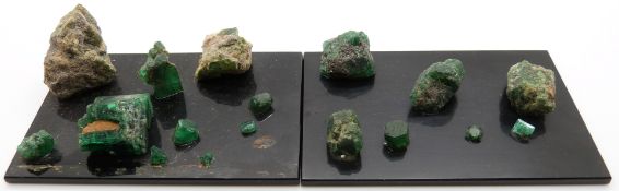 Eighteen loose emeralds mounted on two display boards