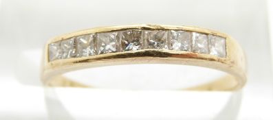 A yellow metal ring set with nine princess cut diamonds