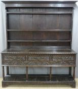 Large 19th century carved oak dresser having plate rack with boarded back, the base fitted three