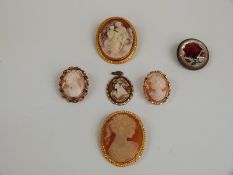 Two cameo brooches, a reverse painted glass brooch and three other brooches