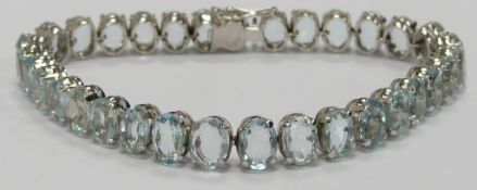 A white metal tennis bracelet set with 31 oval aquamarines each approximately 0.44ct (total approx