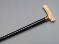 A 19thC walking cane with ivory handle and repoussé decorated collar marked 15ct Gf