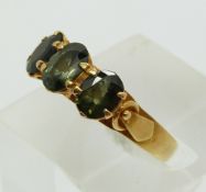 An 18ct gold ring set with three green sapphires (size J)