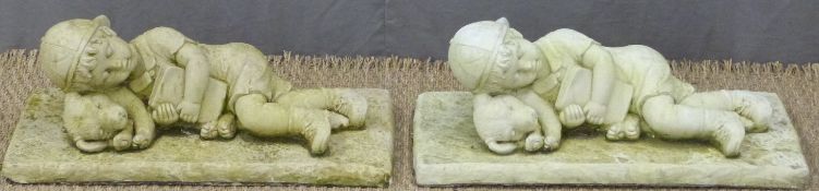 A pair of garden figures of a boy sleeping, length 57cm