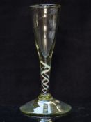 An 18thC clear glass drinking glass with red, white and blue twist decoration to the stem, raised on