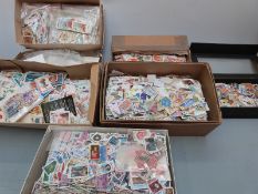 A tray containing a substantial quantity of loose all world stamps in tins, packets etc