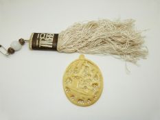 A carved Chinese ivory pendant depicting a river scene and a silk Chinese tassel