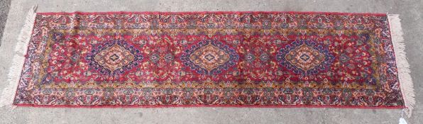 Red ground wool runner rug with three central guls, 2120x60cm