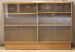 Early to mid 20th century light oak bookcase with adjustable shelves behind sliding glass doors,