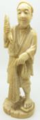 A 19thC Japanese carved ivory figure depicting a man holding a fish and net, 11.5cm tall