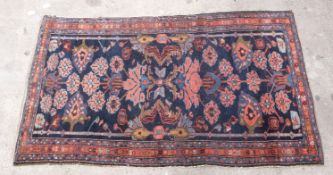 Blue ground handmade rug with stylised floral design, 170x100cm