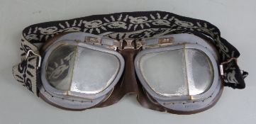 A pair of flying goggles with brassed framed leather backed surround
