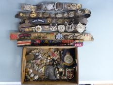 A large collection of military badges mounted on leather belts and loose, includes cloth examples,