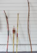 A yew wood long bow, two other bows and a quantity of arrows, longest 160cm