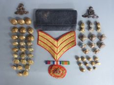 A collection of military buttons, three regimental badges, officer's baton and tobacco pouch with