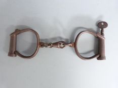 A pair of Hiatt wrought iron handcuffs with key