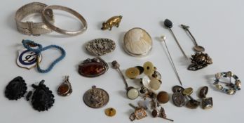 A collection of jewellery including a pressed amber brooch, a silver bangle, two jet earrings, a