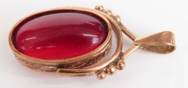 A yellow metal fob set with a red cabochon