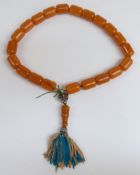 An amber prayer bead necklace of 21 cylindrical beads, each 21.5x15.6mm, with white metal mounts,