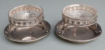 Pair of George V hallmarked silver salts with clear cut glass liners raised on three legs with