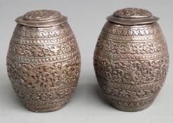 Pair of Indian, Burmese or similar white metal peppers with embossed decoration, height 7cm,