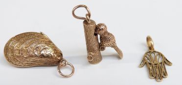 A 9ct gold woodpecker charm (3.1g), a silver gilt shell charm and a filigree hand pendant