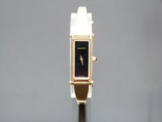Gucci gold plated ladies wristwatch ref. 1500L with gold hands, black dial and quartz movement, on