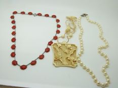 An early 20thC carved ivory pendant, a cultured pearl necklace and an other necklace