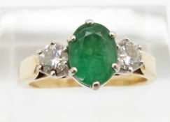 An 18ct gold ring set with an oval cut emerald of approximately 1ct and two diamonds, each