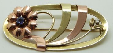 A 14k gold brooch in a stylised floral design set with a diamond and sapphire, 5.2 x 2.5cm, 7.7g