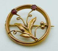 A 9ct gold brooch set with two garnets in a floral design by E.W, 1.9g
