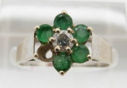 A 9ct white gold ring set with a diamond and emeralds, 2.6g, size N